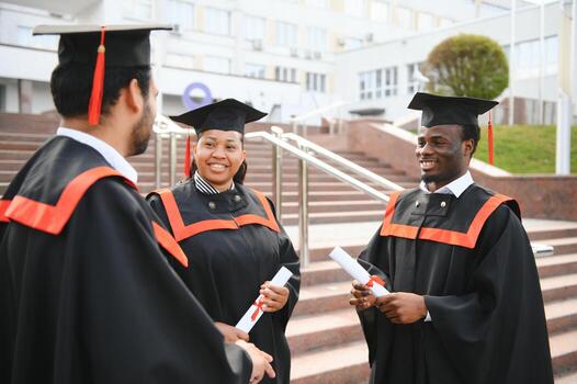 Happy international graduates in mortar boards and gowns celebrating with their diplomas